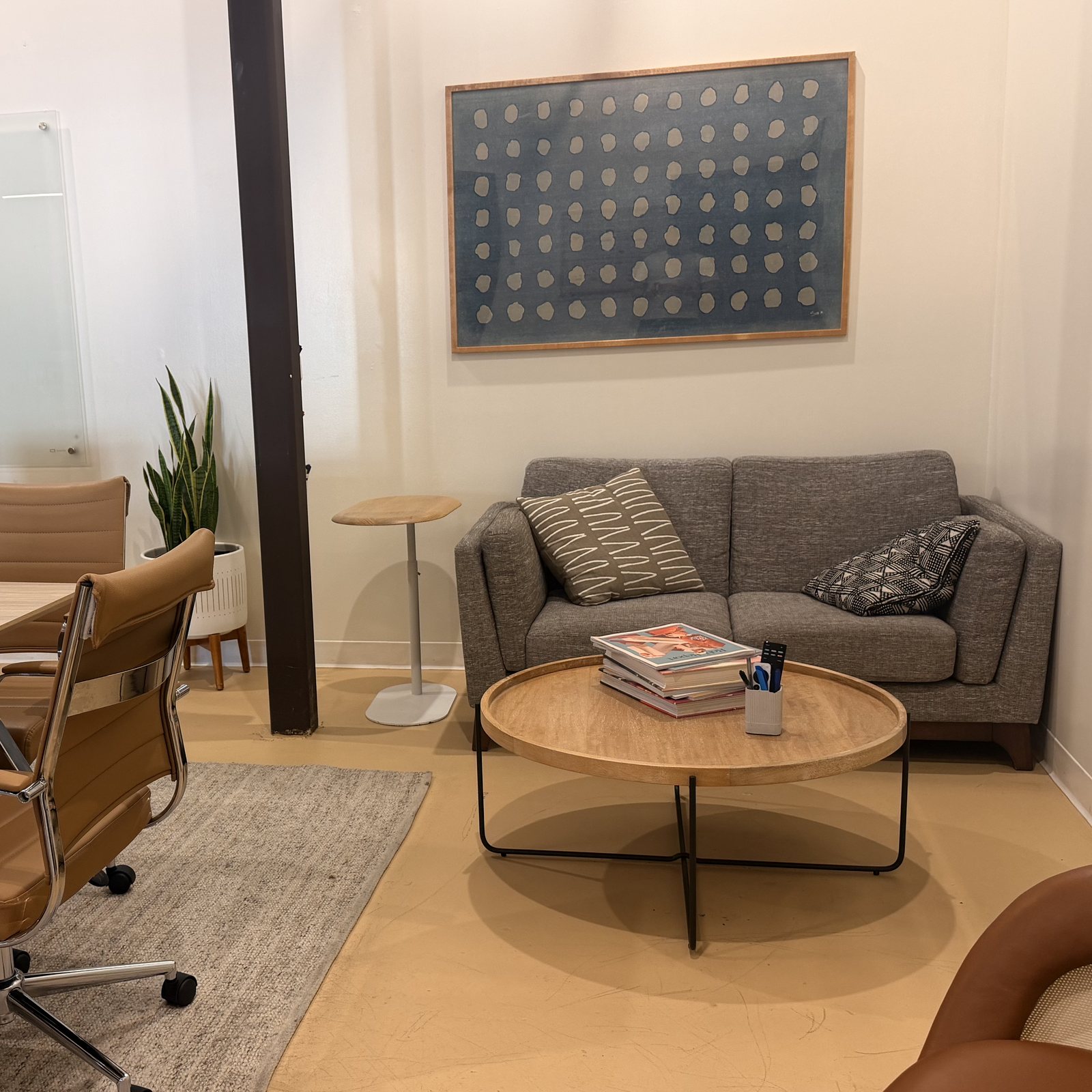 The Conference Room&rsquo;s lounge corner, with a gray sofa, a round coffee table and a framed print